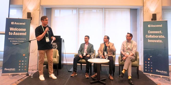 From complexity to clarity: what i heard from risk & compliance leaders at ascend grc toronto 5 A speaker stands with a microphone next to a seated panel of three professionals during a session at ascend grc day in toronto. Two branded signs on either side read “welcome to ascend” and “connect. Collaborate. Innovate. "