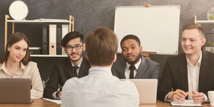 Three men and one woman sitting at a table facing one man representing human resources risk management