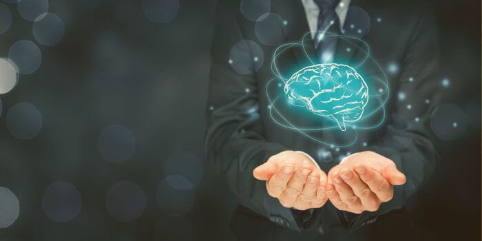 Man wearing suit and tie extending his arms and holding out cupped hands with digital icon of a human brain over them representing machine learning in risk management