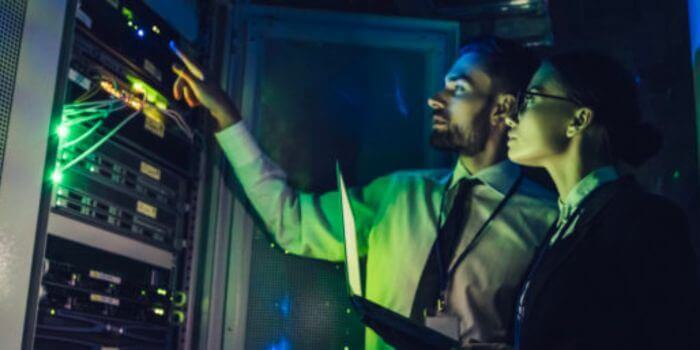One man and one woman in business attire looking at a screen representing vulnerability management