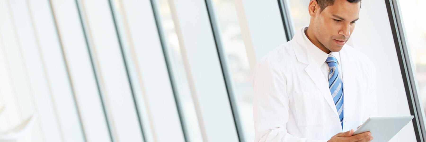 Doctor using digital tablet in corridor of modern hospital to represent risk assessments and regulatory compliance in healthcare