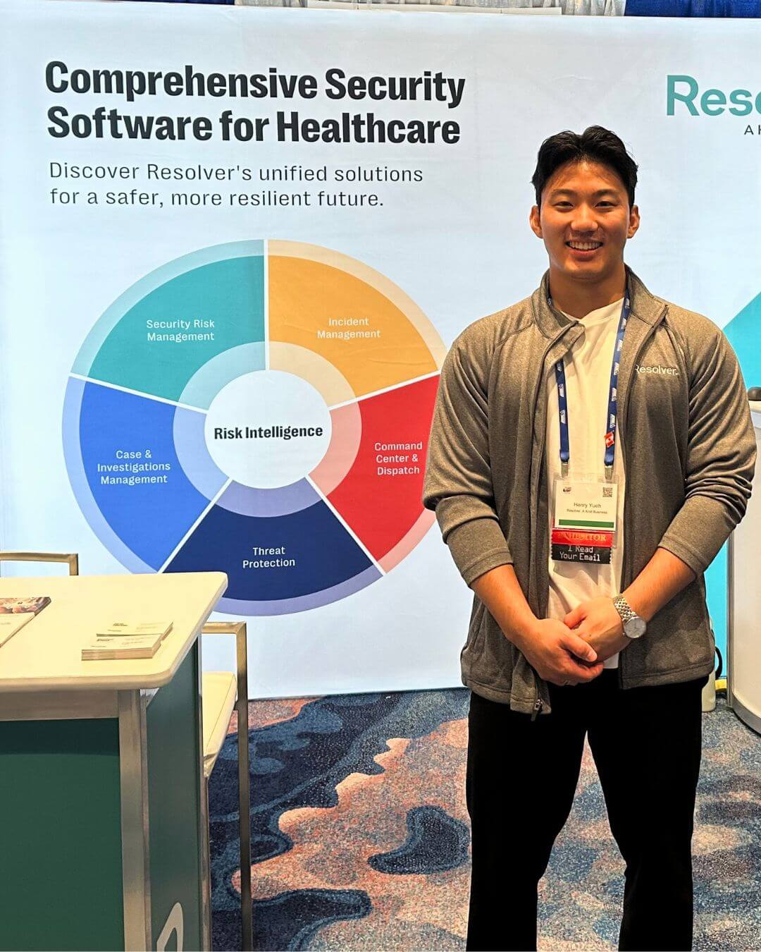 Exploring community & innovation at iahss 2024 5 A resolver representative stands next to a booth at the iahss 2024 conference. Behind them is a display featuring a colorful wheel labeled "risk intelligence," highlighting various aspects of comprehensive security software for healthcare, including incident management, security risk management, and more.