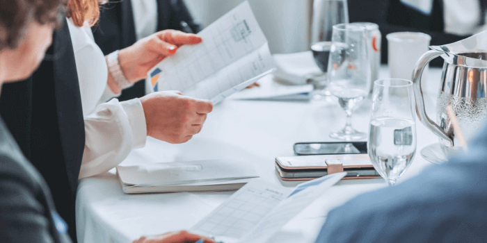Participants at resolver's grc day 2024 engaging in a group discussion on prioritizing grc software enhancements with photo focus on a hand holding a ux assignment paper.