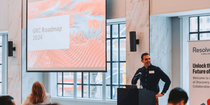 Resolver's director of grc products, ryan napoleone, stands by the podium with a "grc roadmap 2024" slide on the screen behind him at the resolver grc day 2024 event.